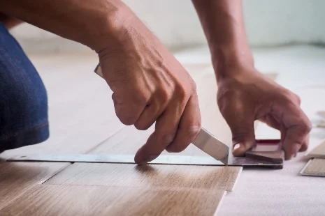 Person schneidet Bodenfliese mit Messer